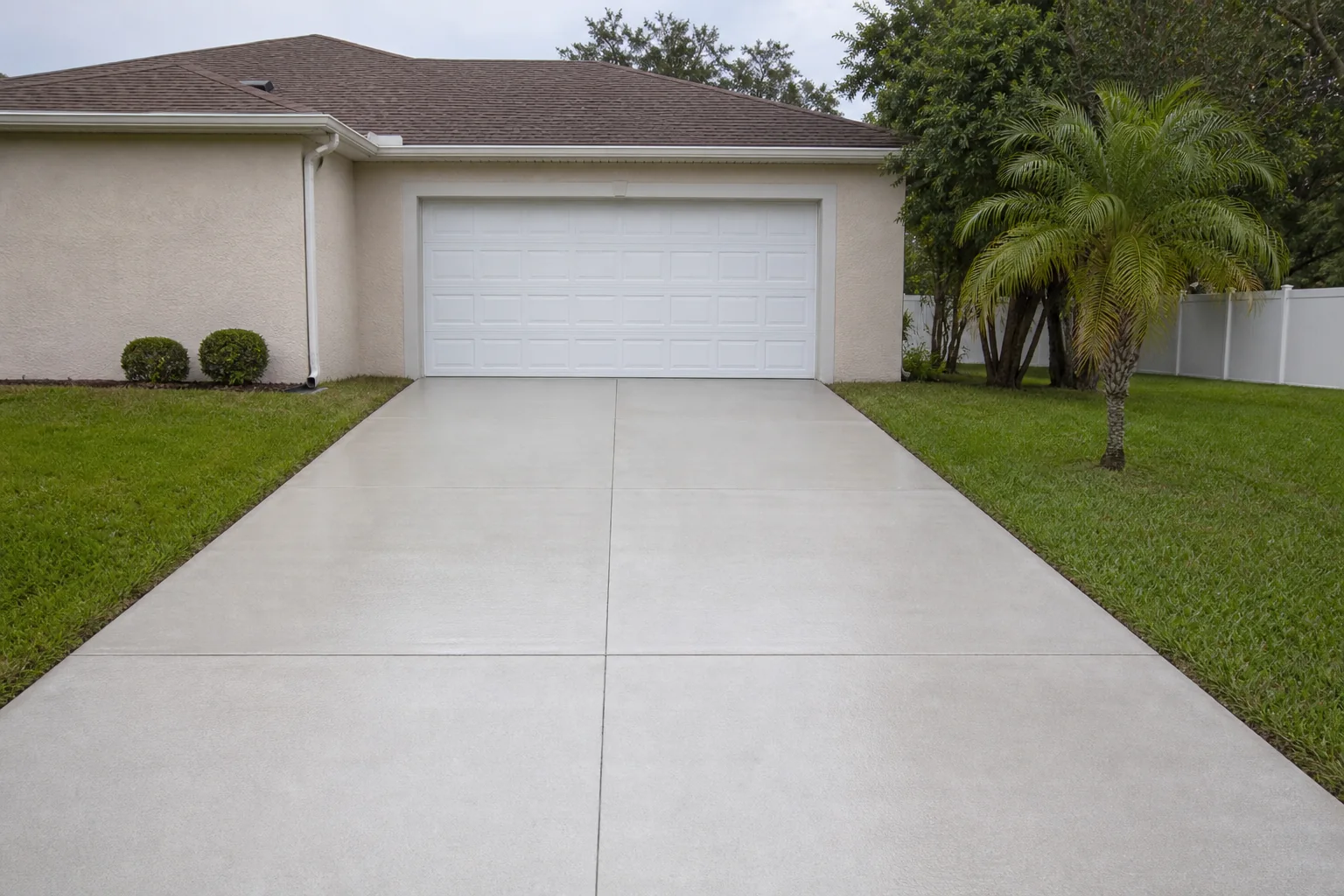 After: freshly cleaned light-gray concrete driveway after pressure washing